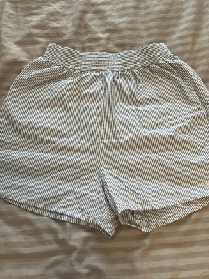 Blå vit randiga shorts från Djerf Avenue - Säljer ett par super mysiga shorts perfekta för sommaren från djerf, i blå vit randigt mönster i storlek xs. Bra kvalitet, det enda är att det har råkat spricka i sidan vid resåren(se sista bilden) men går enkelt och sy ihop igen. 