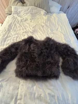 Mörkgrå fluffig pälsjacka - Supersnygg mörkgrå pälsjacka med fluffig och känsla. Jackan har lång ärm och en croppad passform som ger en siluett. Materialet är fuskpäls. Storlek M men sitter mer som en S