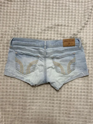Lågmidjade hollister jeansshorts vintage ljusblåa  - Ljusblåa vintage minishorts från hollister. Stora i storleken så sitter mer som en w26-w27 än de som står på lappen. Se mått! Midjemått:38cm stretch till 40cm. Total längd på ena benet fram:17cm. Köp sker via köp nu, jag postar inom 24h. Kvar tills markerad såld 