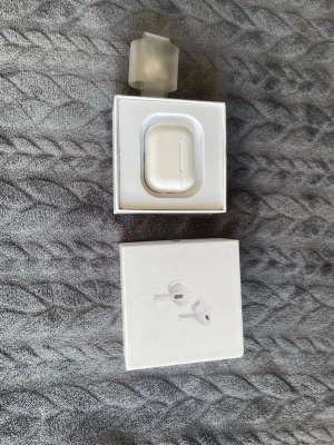 Vita trådlösa hörlurar med laddningsetui - Säljer ett par vita trådlösa hörlurar från Apple med tillhörande laddningsetui. Hörlurarna har en stilren och kompakt design och levereras i originalförpackning. Perfekta för musik, samtal och träning. Smidig anslutning till iPhone och andra Apple-enheter.