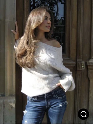 Off shoulder stickad tröja i beige - Slutsåld trending beige stickad tröja med bred off shoulder-ringning och slappa ärmar. Tröjan har ett diskret kabelstickat mönster och är gjord i mjukt material som känns skönt mot huden. Perfekt för en avslappnad och snygg look. Modellen på bilden har storlek S! Är endast använd en gång!
