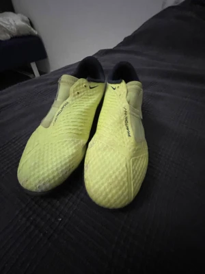 Nike Phantom Vision gula fotbollsskor - Säljer ett par Nike Phantom Vision fotbollsskor i en riktigt snygg gul färg med svart swoosh på sidan. Skorna har en modern, strömlinjeformad design och är tillverkade i syntetmaterial för bra bollkontroll. Perfekta för dig som vill sticka ut på planen.