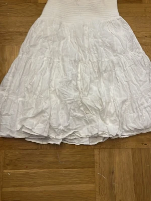 Vit kortklänning från Zara - Säljer en söt vit kortklänning från Zara med smock upptill och volangig kjol. 