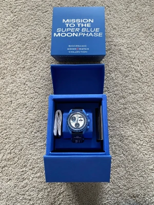 Blå Omega x Swatch Super Blue Moon klocka - Säljer en blå Omega x Swatch Mission To The Superblue Moon MoonSwatch med blått armband och vit urtavla. Klockan har flera subdials och tydliga markeringar runt boetten. Kommer i originalförpackning med manual och certifikat.