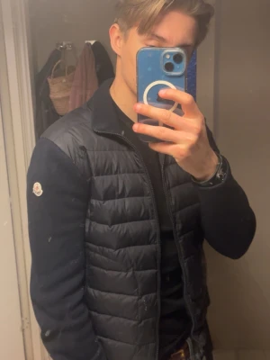 Svart dunväst från Moncler - Snygg svart dunväst från Moncler med quiltad front och ärmar i mjukt tyg. Klassisk passform med dragkedja och diskret Moncler-logga på ärmen. Perfekt för lager-på-lager och en stilren look.