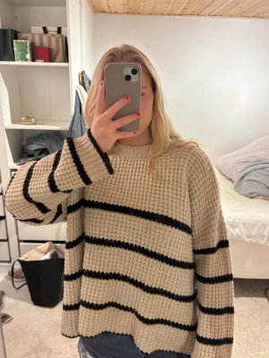 Randig tröja - Säljer en oversized beige stickad tröja med svarta horisontella ränder. Tröjan har rund halsringning, lång ärm och grovstickad struktur som ger en avslappnad look. Perfekt för dig som gillar en enkel men trendig stil. Den köptes på Sellpy i oanvänt skick och är fortfarande i mycket bra skick. Lite smutsig men tvättar självklart innan jag postar❤️❤️