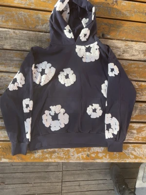 Navy blue denim tears - Snygg denim tears hoodie med stora vita blommönster över hela tröjan. Tröjan är knappt använd och jag säljer den för att den är för stor. Pris för att diskutera är möjligt.