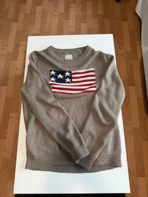 Brun USA stickad tröja - Tja den är i mycket bra skick från Selected Homme i storlek L/Xl. Den är i mycket bra skick men har några små fläckar längst ner på tröjan som säkert går bort i tvätten. Lite över fläckarna så har tröjan tappat lite tyg  på insidan som man inte märker