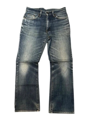 Edwin bootcut jeans - Säljer ett par klassiska blå jeans från Edwin med bootcut passform och fem fickor. Jeansen har snyggt slitna detaljer och en vintagekänsla. Tillverkade i kraftig denim med läderpatch bak i midjan. Perfekta för en avslappnad och tidlös stil. Midjebredd:40cm Totallängd:99.5cm Benöppning:22cm