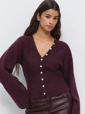 Plommonlila kofta med knappar - Trendig plommonlila kofta från Monki med v-ringning och vita knappar längs hela framsidan. Koftan har bred ribbstickad midja och vida ärmar för en avslappnad look. Perfekt att styla med höga byxor eller kjol.