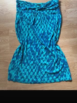 Axelbandslös klänning från Lindex – blå/turkos önstrad, strl M - En riktig sommarklänning som sitter snyggt utan att halka ner   Beskrivning: Stilren och bekväm klänning från Lindex i storlek M. Axelbandslös modell med fint blått och turkost mönster som verkligen sticker ut utan att bli för mycket. Perfekt till sommaren, semestern eller festligare tillfällen.  Upptill finns silikonremsor på insidan som gör att klänningen sitter på plats.  Detaljer: • Storlek: M • Märke: Lindex • Axelbandslös (strapless) • Mjuk och följsam i materialet