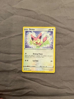 Pokémonkort Skitty - Pokémonkortet Skitty med gul ram och färgglad illustration av Skitty i mitten. Kortet är gjort av papper och har text på engelska med attacker som Drawup Power och Cat Kick. Perfekt för samlare eller Pokémon-fans som gillar klassiska kortspel.