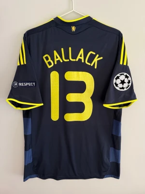 Chelsea 09/10 Away - #13 Ballack - size M - 9/10 - Chelseas away kit used in 2009/10 season with UCL patches and 13 Ballack printed on the back. A navy blue shirts with horizontal stripes and yellow notes on sponsor, logo, stripes and more. A classic UCL shirt honoring the German midfielder Ballack 🔵  Condition: 9/10. Excellent! Size: M Product code: E84276