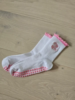 Helt nya Pilates-/yogastrumpor antislip stl 36-39 - Helt nya aldrig använda.  Säljer ett par vita strumpor med rosa volangkant och halkskydd under. Strumporna har broderade rosa hjärtan och rosetter på skaftet. Perfekta för pilates/reformer/yoga  Storlek 36-39 köpta för 79 kr på ett event. 