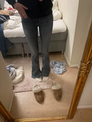 Blå bootcut jeans - Säljer ett par blå bootcut jeans med klassisk femficksdesign och lätt slitning. Jeansen har en snygg passform som är smal upptill och utsvängda nedtill. Perfekta för dig som gillar en avslappnad och trendig look.