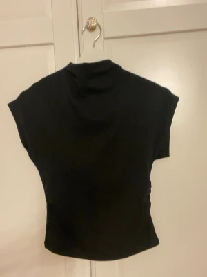 Svart polotopp från Gina Tricot  - Snygg svart polotopp från Gina TricotToppen har korta ärmar och hög hals och slimmad midja denna är okså helt oanvänd utan lapp super mjukt material 