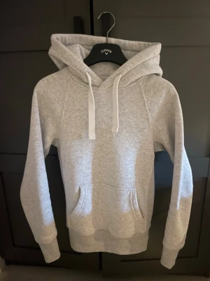 Ljusgrå hoodie - En nästintill oanvänd stilren ljusgrå Russemerch hoodie med magficka och vita dragsnören i huvan. Hoodien har ribbade muddar vid ärmslut och nederkant, samt en klassisk passform. Perfekt för en avslappnad look och enkel att matcha med andra plagg. inga missdofter eller fläckar.😊