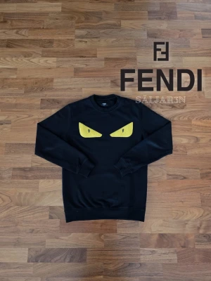 Svart Fendi Sweatshirt - 🖤 Fendi Sweatshirt – Svart | Storlek S 🖤 Stilren Fendi sweatshirt i svart med ikoniska gula ögon på bröstet som ger ett unikt uttryck. Tillverkad i mjuk, högkvalitativ bomull för maximal komfort. Lång ärm med ribbade fållar och ärmslut ger bra passform. Rund halsringning och enkel design gör den lätt att matcha. Nyskick, taggen sitter kvar. 📦 Snabb leverans – Kontakta för frågor!