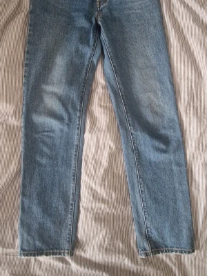 Blå raka jeans, Levis 501 - Ett par blå jeans, Levis 501, med rak passform och normal midja. Jeansen har en klassisk femficksdesign och är tillverkade i denim med lätt tvättad look. Storlek 25/30, vilket motsvarar ungefär xs.