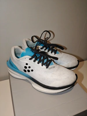 Craft pro endurance distance löpskor 40 - Snygga vita sneakers från Craft med blå detaljer och svart sula. Skorna har svarta snören och är tillverkade i ett lätt och ventilerande material. De har en låg profil och en modern design med Craft-loggan på sidan. Kommer från rökfritt och djurfritt hem. Storlek 40 men passar bäst för dig som har 39 eller 39,5