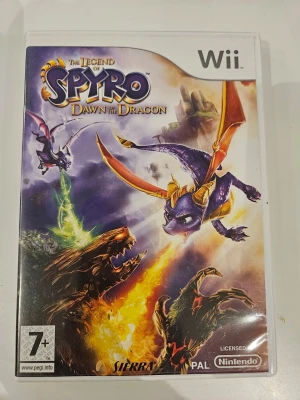 The Legend of Spyro: Dawn of the Dragon Wii - The Legend of Spyro: Dawn of the Dragon till Nintendo Wii. Ett actionäventyr där du spelar som drakarna Spyro och Cynder, slåss mot bossar och kan flyga fritt. Omslaget är färgglatt med lila och orange drakar och fantasy-motiv. PAL-version, licensierad av Nintendo och Sierra.