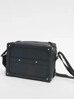 Svart boxig axelväska med nitar - Cool svart axelväska i boxig form med justerbar rem. Väskan har detaljer med silverfärgade nitar och förstärkta hörn. Tillverkad i slitstarkt tygmaterial och stängs med dragkedja upptill. Perfekt för dig som gillar en stilren och edgy look.