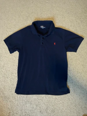 Mörkblå piké från Polo Ralph Lauren - Klassisk mörkblå pikétröja från Polo Ralph Lauren i mörkblå. Vädligt bra skick. Den är i storlek M men den är lite mindre i storleken så skulle säga mer S. Fråga gärna om du har mågra frågor. Skickar inom 24h!