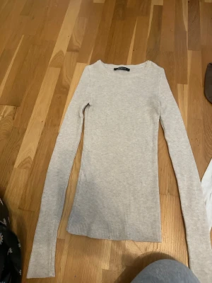 Beige ribbad långärmad tröja - Slimmad beige långärmad tröja i ribbat material med rund halsringning. Perfekt basplagg som är lätt att matcha och har en mjuk, stretchig känsla. Enkel och stilren design utan synliga detaljer eller tryck.