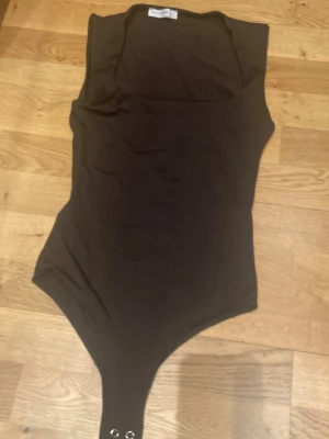 Mörkbrun body🤎 - Säljer en enkel och stilren mörkbrun body med breda axelband och rund halsringning. Bodyn har tryckknappar i grenen för enkel på- och avklädning. Perfekt att matcha med jeans eller kjol för en clean look. Har använt väldigt lite eftersom att jag trivdes inte i att ha body med super fin annars. 🥰🤎💕