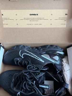 Nike D/MS/X svarta sneakers - Svarta Nike D/MS/X sneakers med futuristisk design, reflekterande detaljer och synlig luftdämpning i hälen. Ovandelen är i mesh och syntetmaterial för bra andningsförmåga. Swoosh-logga i vitt och robust sula med vågig struktur för extra grepp. 