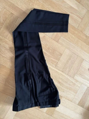 Svarta kostymbyxor från ASOS DESIGN - Snygga svarta byxor till smoking från ASOS DESIGN med raka ben och diskreta pressveck och revär. Tillverkade i ett mjukt, vävt material som ger en clean och stilren look. Perfekta för dig som vill ha en klassisk men modern vibe.