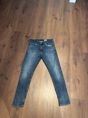 Tiger of sweden jeans - Snygga blå slim fit jeans med lätt slitna detaljer och klassisk femficksdesign. Jeansen har normal midja och smala ben, perfekt för en trendig och avslappnad stil. Passar till det mesta och är ett måste i garderoben.