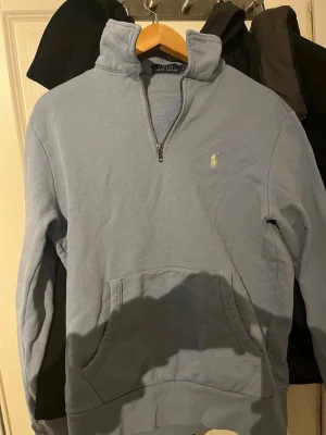 Ljusblå halvzip hoodie Polo Ralph Lauren - Säljer denna tröja då den var för liten på mig. Köpte den för 2000 sek och har använt den 2 gånger. Storlek S