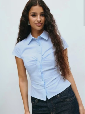 Kortärmad skjorta - Säljer en helt ny ljusblå kortärmad skjorta med prislappen kvar i storlek 34 från Gina tricot 