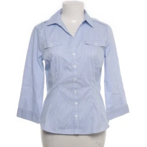 Blåvit randig blus med trekvartsärm - Snygg blåvit randig blus med trekvartsärm och klassisk krage. Blusen har knäppning framtill och två bröstfickor med lock. Perfekt för en stilren och fräsch look. Materialet känns lätt och bekvämt. Står 40/L men passar mer S-M 