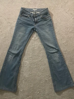 Ljusblå bootcut jeans - Snygga ljusblå bootcut jeans med klassisk femficksdesign och lätt slitning framtill. Jeansen har broderade detaljer på bakfickorna och är tillverkade i denim med lite stretch för extra komfort.