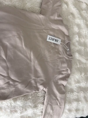 Beige sweatshirt från OBJECT - Säljer en stilren beige sweatshirt från OBJECT med rund halsringning och långa ärmar. Tröjan har en enkel design och är tillverkad i mjukt material som känns skönt mot huden. Perfekt för en avslappnad look.
