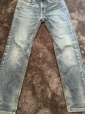 Ljusblå jeans från Lindex - Snygga ljusblå jeans från Lindex med klassisk femficksmodell och raka ben. Jeansen har slitningar och kontrastsömmar för en trendig look. Perfekta för dig som gillar en avslappnad stil. Materialet är denim i bomull.