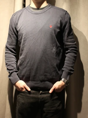 Mörkblå stickad tröja från Morris - Mörkblå stickad tröja från morris med rund halsringning och ribbade muddar. Tröjan har en liten röd broderad logotyp på bröstet och är tillverkad i ett mjukt material som passar perfekt till jeans. ‼️några småfläckar som syns på bild nmr 2 och 3 men annars toppskick‼️ modellen är 182 cm lång och bär vanligtvis S/M🌟 hör gärna av dig med frågor🤝