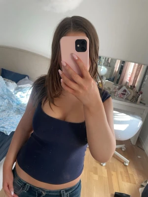 Marinblå topp - Snygg mörkblå croppad linnetopp med breda axelband och rundad urringning. Perfekt till jeans eller kjol för en enkel och stilren look. Från Brandy Melville💕