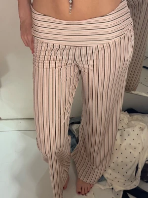 Helt nya fina byxor - Säljer ett par superbekväma leggings med hög midja och vida ben. De är ljusrosa med svarta och vita vertikala ränder. Materialet är stretchigt och mjukt, perfekt för en chill och avslappnad stil. Inget synligt märke på byxorna.