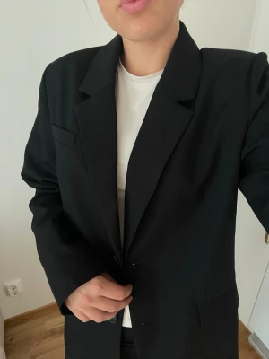 Svart oversized kavaj - Stilren svart oversized kavaj med klassisk krage och två knappar framtill. Använd 1 gång. Storlek S passar M i och med att den är oversized