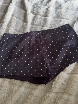 Mörka prickiga pyjamas shorts  - Säljer ett par mörka shorts med vita prickar. De har en klassisk passform och är perfekta för en mys kväll 