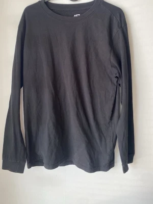Svart långärmad tröja från 4F - En basic svart långärmad tröja från 4F med rund halsringning. Tillverkad i mjukt bomullsmaterial och har en enkel, clean design utan tryck eller mönster. Perfekt att styla lager på lager eller bära som den är.