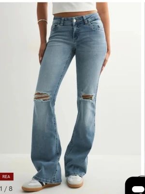 Blå bootcut jeans med slitningar - Säljer ett par ljusblå bootcut jeans från nelly med slitna detaljer över knäna. Jeansen är lågmidjade. Aldrig använda!!! Helt nya endast testade &  Prisplappen e kvar och jag säljer pga de är för långa för mig. Jag är 158 cm. Originalpris 699kr. Skriv till mig vad du kan betala, ifall du är intresserad. 