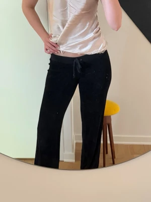 Juicy Couture vintage byxor - Snygga svarta Juicy Couture vintage mjukis byxor i storlek S🫶 De är low waist och bootcut, fint skick förutom ett hål på baksidan som jag för många år sedan lagat med en lapp på insidan, inget man tänker på men de två sista bilderna i annonsen visar hur det ser ut! 