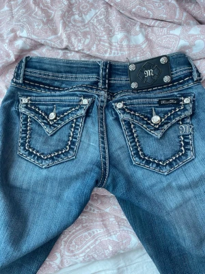 Miss Me blå jeans med detaljer - Snygga blå jeans från Miss Me. De har varit skinny men sytt till bootcut. Modellen är från 2000 talet. Midjan är 35 cm och innerbenslängden är 76 cm. 