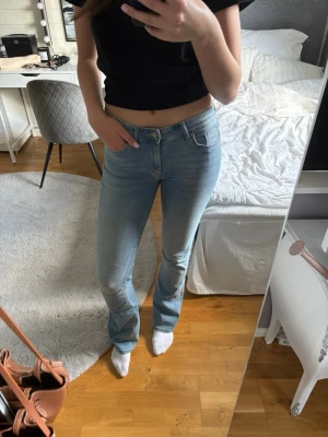 Ljusblå bootcut jeans - Säljer ett par ljusblå bootcut jeans med klassisk femficksdesign och normal midja. Jeansen har en snygg tvätt och är tillverkade i stretchigt denimtyg för skön passform. Perfekta till en avslappnad look.