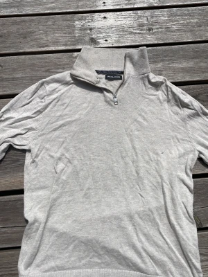 Beige stickad tröja med halvzip - Snygg ljusgrå stickad tröja från Jack & Jones med hög krage och halv dragkedja. Perfekt för lager-på-lager och enkel att matcha med jeans eller chinos. Tröjan har ribbade muddar och är tillverkad i mjukt material.