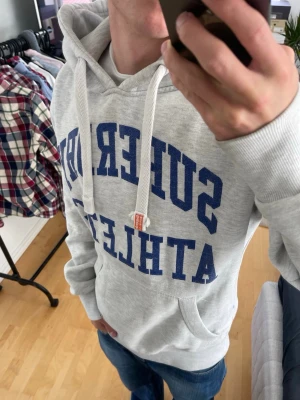Ljusgrå vintage 2000s Superdry hoodie (sällsynt) - Säljer nu denna sjukt snygga Vintage 2000s SuperDry hoodie! Passar till allt och har en perfekt passform. Säljs ej längre i butik och är därav mycket eftertraktad😊 passar L eller en stor M perfekt. Skriv vid funderingar 🤝